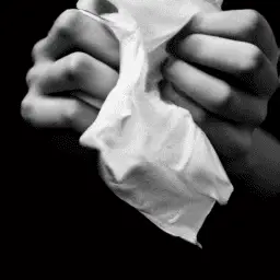 A black and white photo of a hand holding a tissue.
