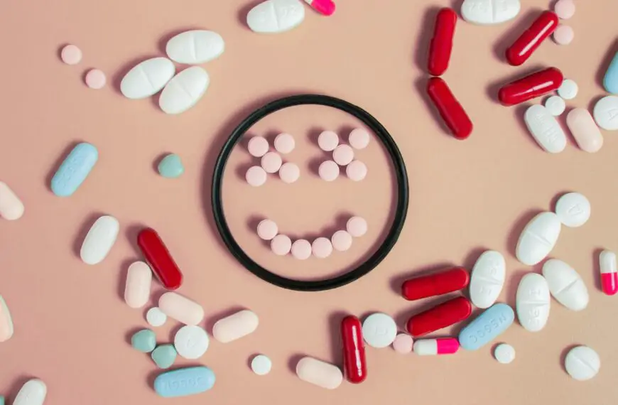 Assorted pills and capsules arranged around and inside a circular dish, forming a smiling face on a pastel background.